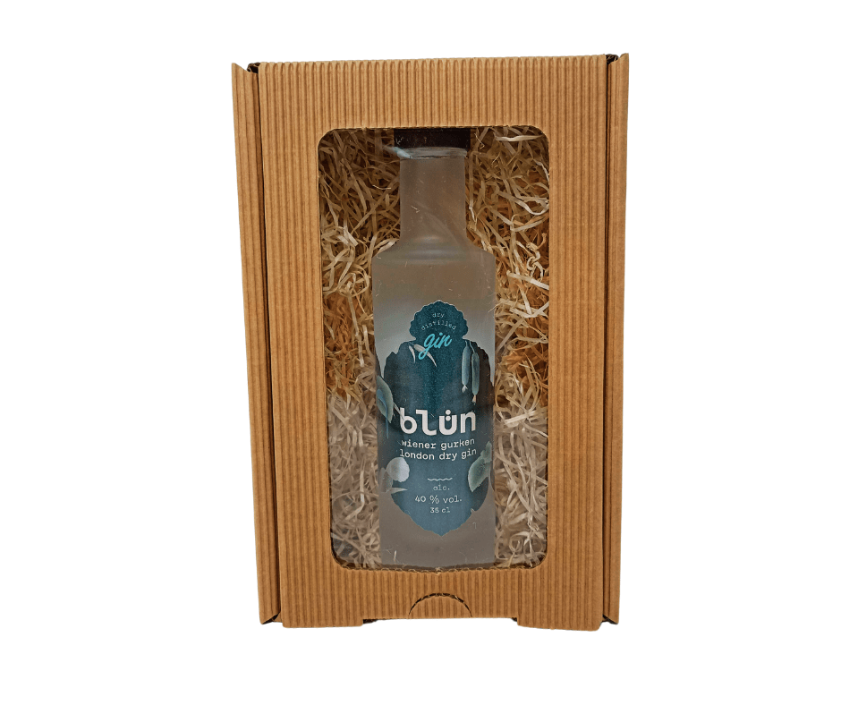 Frosted glass bottle of London Dry Gin with blue label inside a brown corrugated gift box with clear window and straw filler.