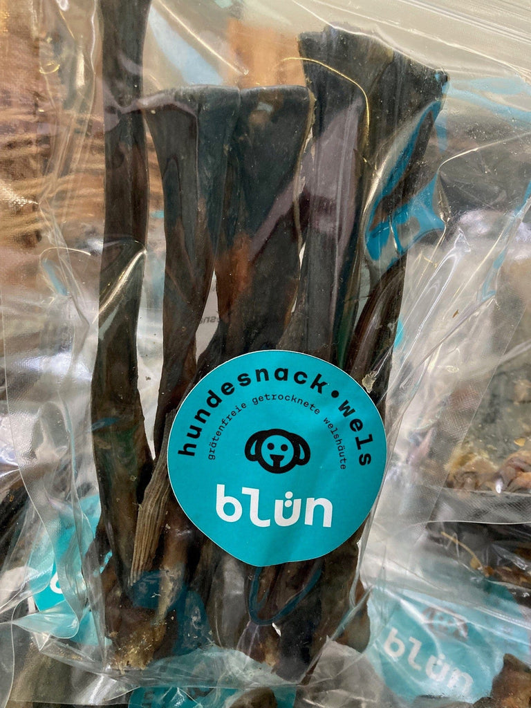 Clear plastic bag of dark brown or black dried dog treats with blue label reading hundesnack.welte blün.