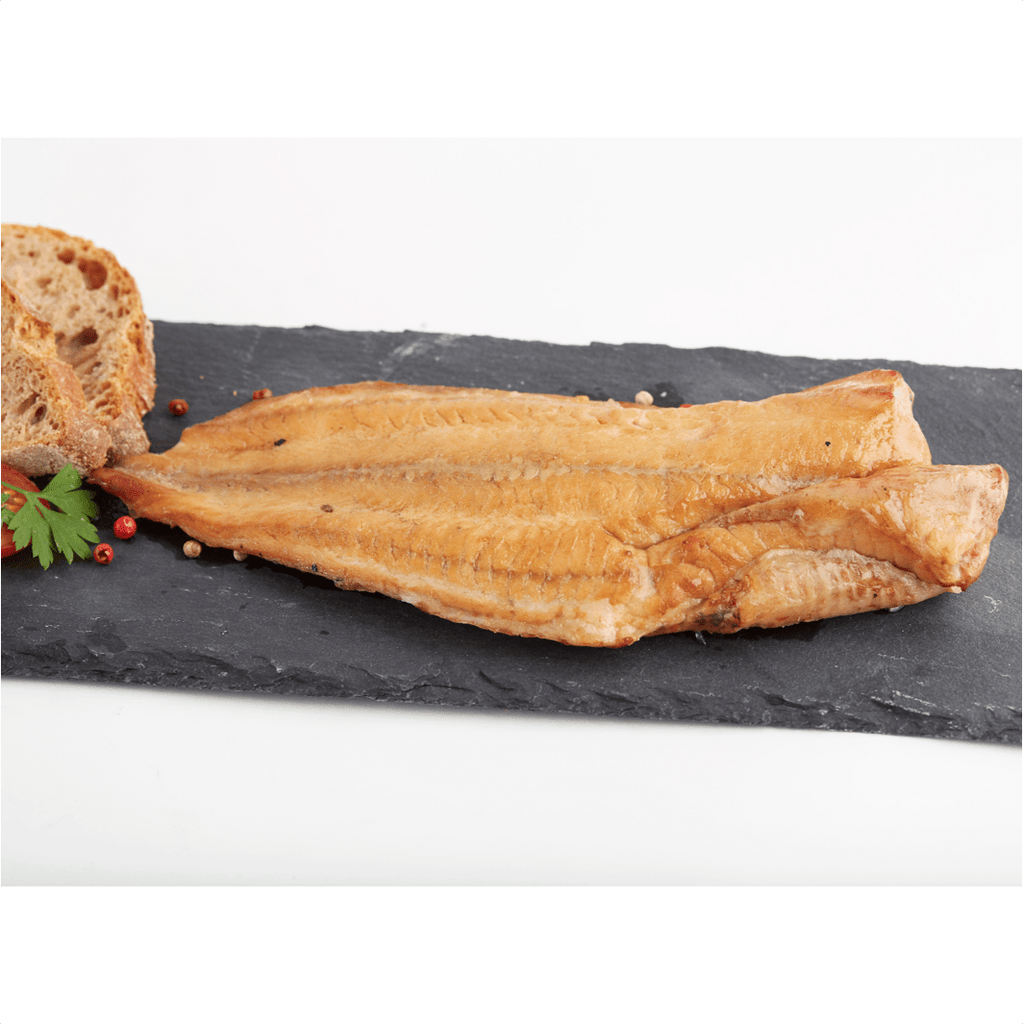 Smoked wiener wels fish fillet on black slate with bread and parsley garnish.
