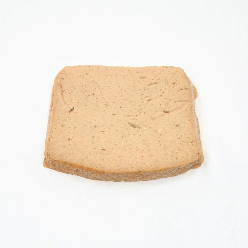 Rectangular slice of light brown Wiener Wels Leberkäse with smooth texture on white background.
